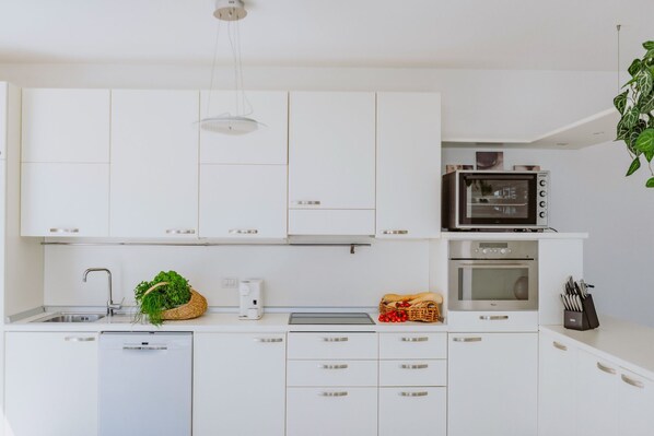 A modern kitchen with white cabinets, a built-in microwave, a toaster, and a dishwasher. - Casa Delle Arche - Five Bedroom Villa, Sleeps 10 (Gardone Riviera)