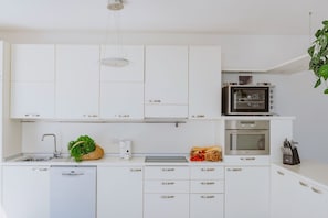 A modern kitchen with white cabinets, a built-in microwave, a toaster, and a dishwasher.