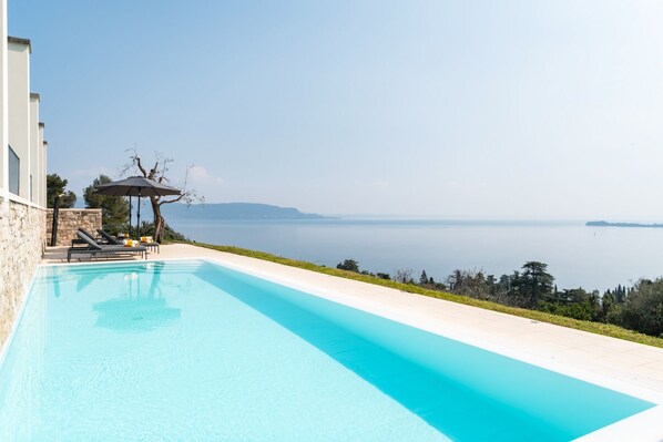 A swimming pool with lounge chairs and a pergola, overlooking a calm sea and distant mountains. - Casa Delle Arche - Five Bedroom Villa, Sleeps 10 (Gardone Riviera)
