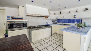 A kitchen with white cabinets, a gas stove, a built-in oven, and blue-tiled backsplash.