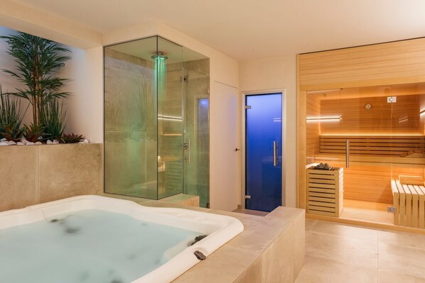 A modern spa area with a hot tub, a glass-enclosed shower, and a sauna.
