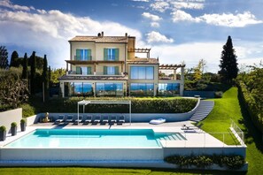 A modern two-story house with a swimming pool, outdoor seating, and a well-maintained garden.