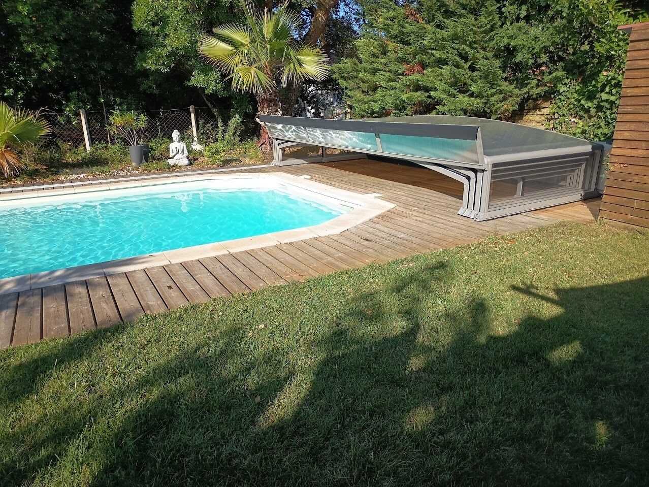 A swimming pool with a wooden deck and a covered area.