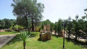 A garden with a stone bench, a lamppost, and a palm tree. - Torre del Drago - Three Bedroom Villa, Sleeps 6 (Marina di Felloniche)