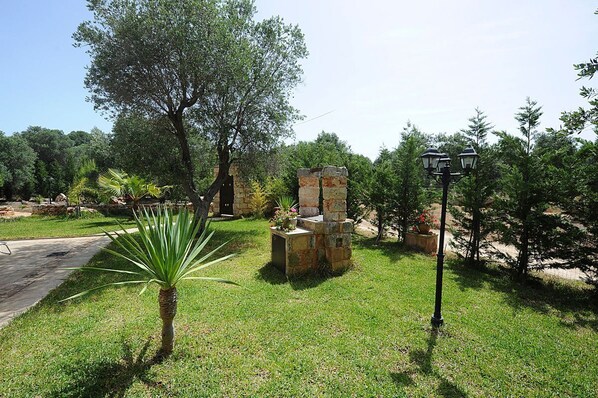 A garden with a stone bench, a lamppost, and a palm tree. - Torre del Drago - Three Bedroom Villa, Sleeps 6 (Marina di Felloniche)