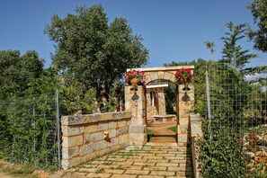A stone pathway leading to a rustic stone structure with a wooden door and a small bench. - Torre del Drago - Three Bedroom Villa, Sleeps 6 (Marina di Felloniche)
