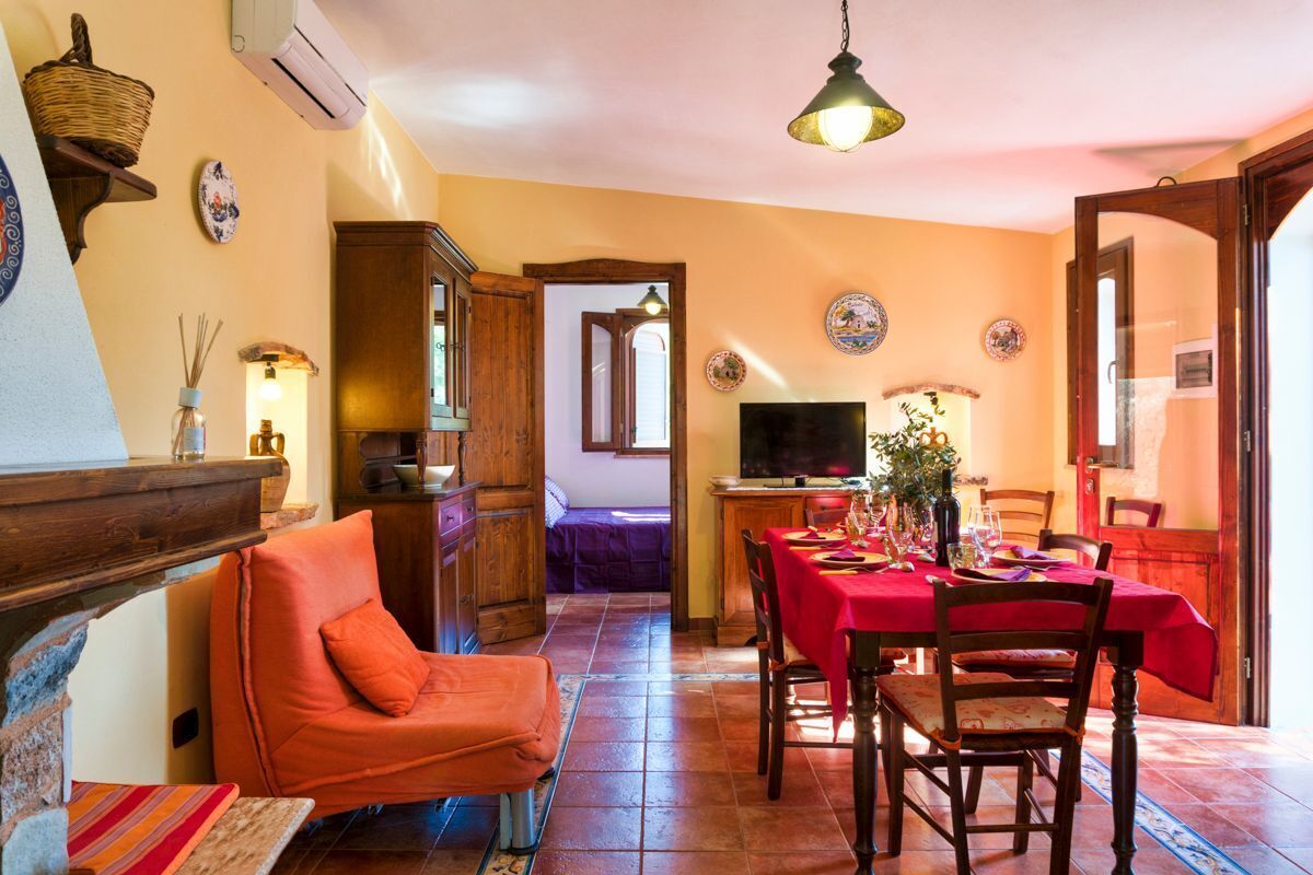 Un'accogliente sala da pranzo con tovaglia rossa, sedie di legno e televisore.