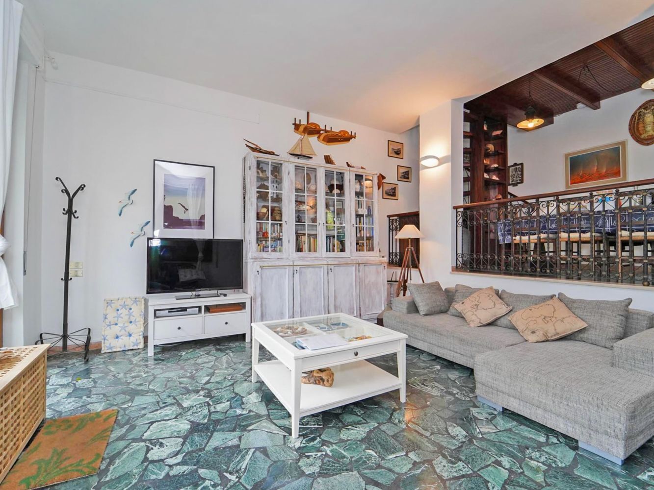 A living room with a television, a cabinet with glass doors, a sofa, and a patterned floor.
