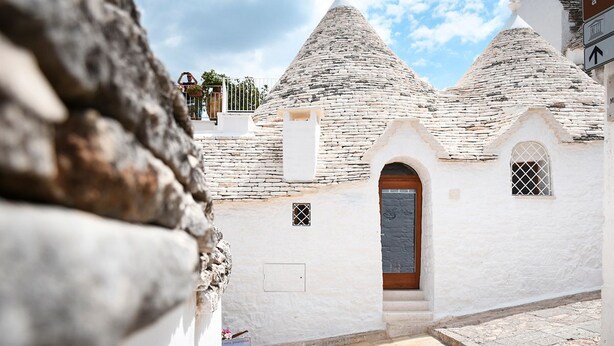 A traditional stone building with a conical roof, a wooden door, and a small window.