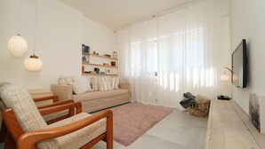Una sala de estar moderna con un sofá, dos sillas de madera, una mesa de centro y un televisor.