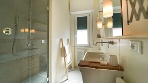 Un baño moderno con cabina de ducha de vidrio, tocador de madera y un espejo grande.
