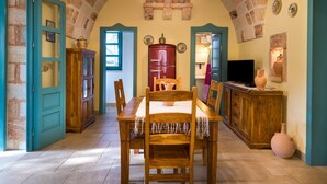 Un coin repas rustique avec une table et des chaises en bois, un réfrigérateur rouge et un téléviseur posé sur un meuble en bois.