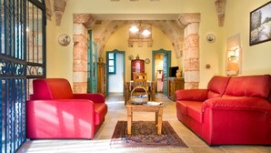 Un salon chaleureux avec des canapés rouges, une table basse en bois et une arche en pierre.