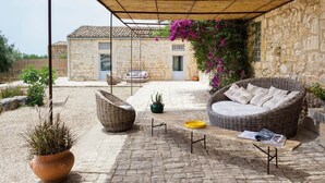 Un espace extérieur abrité, doté de murs en pierre, de meubles en osier et de plantes en pot.
