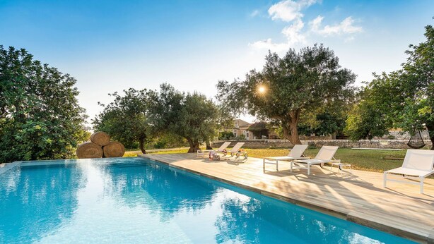 Une piscine avec des chaises longues et une terrasse en bois.
