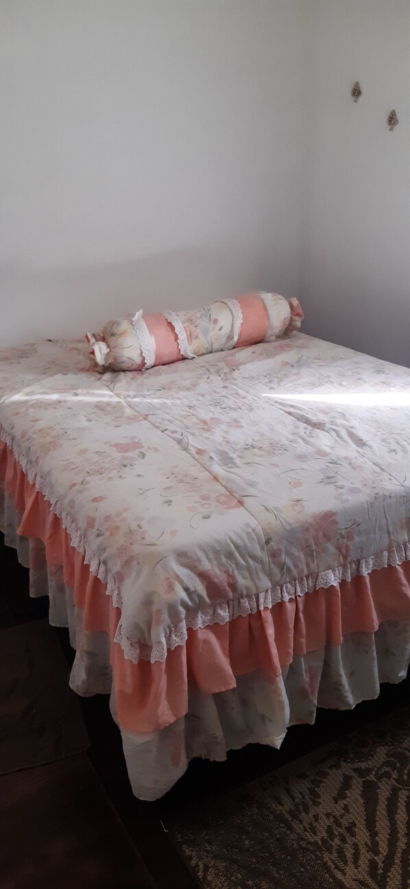 A bed with a floral bedspread and a pink and white pillow. - Well-located apartment in the Estuary area of ​​Santos. (Santos)