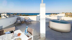 Una terraza en la azotea con piscina, sillones de descanso y una mesa con bebidas y aperitivos.