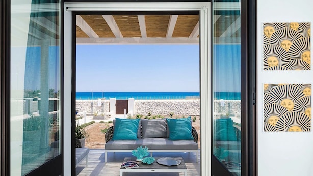 Zona d'estar exterior moderna amb vista a la platja i l'oceà.