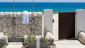 Mur de pedra amb una tovallola penjada, una porta i vista a l'oceà.
