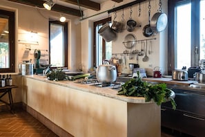 Una cocina con una isla central, ollas colgantes y diversos utensilios de cocina.
