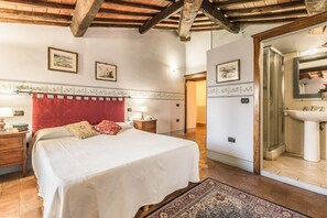 Une chambre avec un grand lit, une tête de lit rouge, une table de chevet, une lampe et une étagère fixée au mur.
