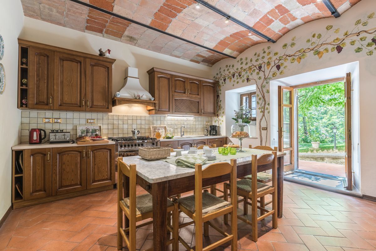 A kitchen with wooden cabinets, a tiled backsplash, and a dining area with a table and chairs.