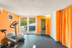 Une salle de sport équipée de matériel d’exercice, d’un grand ballon de gymnastique et d’une porte-fenêtre coulissante donnant sur un espace extérieur.