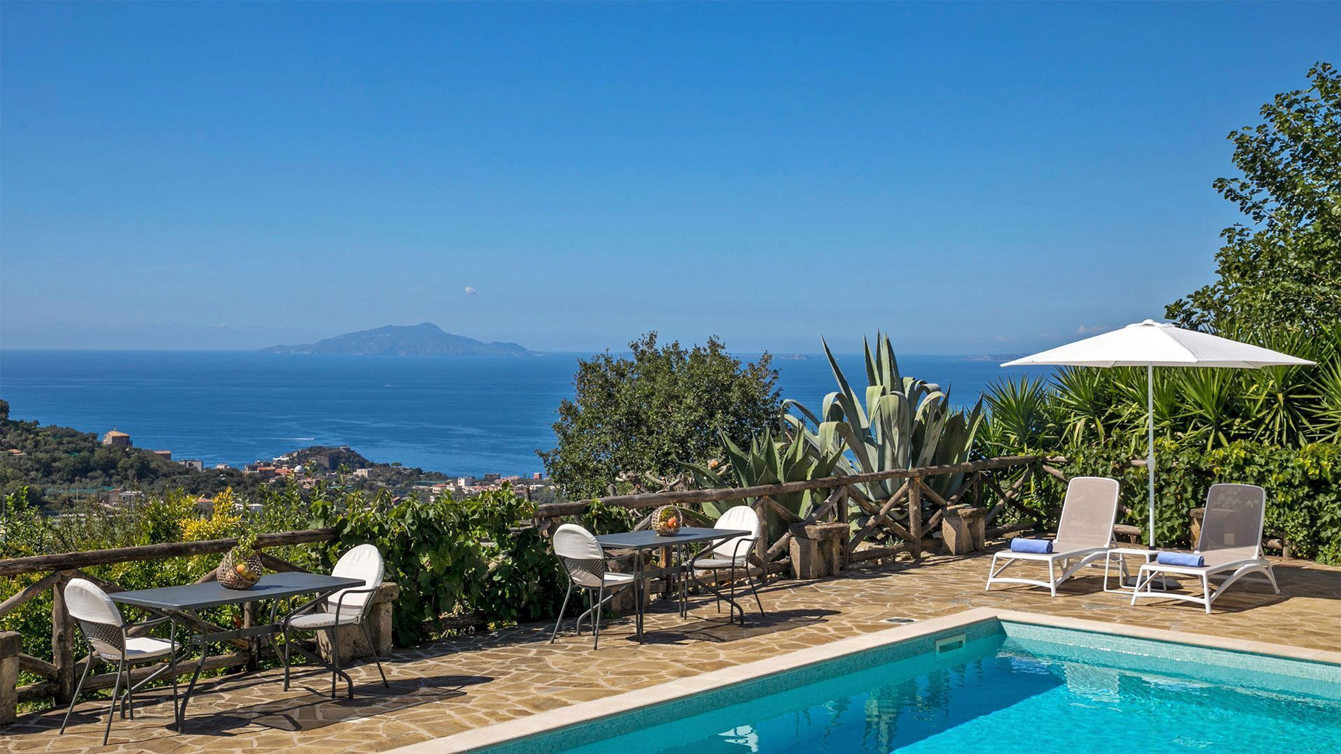 Area piscina con vista sul mare e una montagna sullo sfondo.