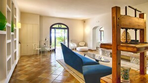 Un vaste espace de vie avec un canapé bleu, des chaises blanches et un escalier en bois.