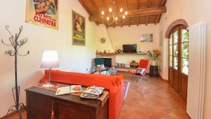 A cozy living room with a wooden ceiling, a fireplace, a television, and a red sofa. - Casa Palanca - Two Bedroom Villa, Sleeps 4 (Capannori)