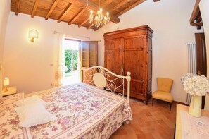 Een slaapkamer met een bed, een houten garderobe, een stoel en een kroonluchter.