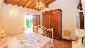 A bedroom with a bed, a wooden wardrobe, a chair, and a chandelier. - Casa Palanca - Two Bedroom Villa, Sleeps 4 (Capannori)