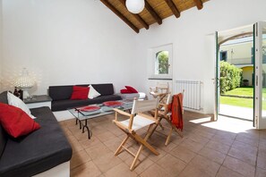 A living room with a sofa, chairs, a table, and a view of the outdoors.