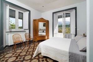 Une chambre à coucher avec un lit, deux chaises, une armoire en bois et une vue sur l’extérieur.