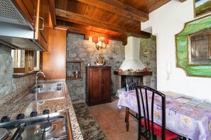 A rustic kitchen with granite countertops, a gas stove, and wooden cabinets.