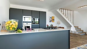 A modern kitchen with a central island, dark cabinetry, and a staircase leading to an upper level. - Cella Mimavi - Three Bedroom Villa, Sleeps 6 (Ribera)