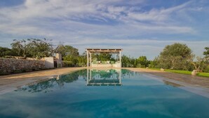 Une piscine aux eaux cristallines, avec une pergola et des chaises longues en arrière-plan.