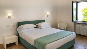 A bedroom with a bed, bedside tables, a chair, and a window.