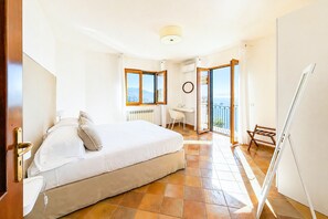 Ein Hotelzimmer mit Bett, Schreibtisch, Stuhl und einem Balkon mit Blick.