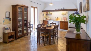 A spacious kitchen with a dining table, wooden cabinets, and a large cabinet with glass doors.