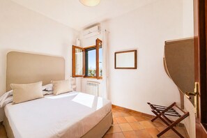 A bedroom with a bed, a window, a radiator, and a chair.