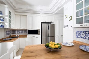 Une cuisine moderne avec des meubles blancs, un réfrigérateur en acier inoxydable, un four à micro-ondes et un plan de travail en bois.