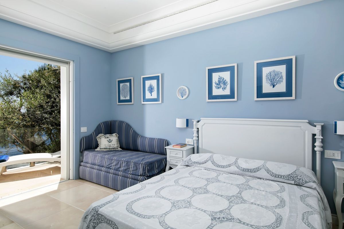 Ein Schlafzimmer mit Bett, Nachttisch, Stuhl und Blick ins Freie.