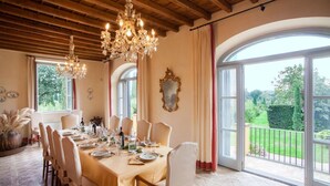 Comedor con una mesa larga dispuesta para seis personas, ventanas amplias y un candelabro.