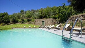 A swimming pool with lounge chairs and a stone building in the background.