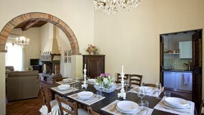 A dining area with a long table set for six, surrounded by wooden chairs.
