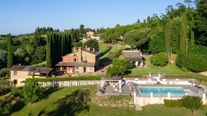 Eine Villa mit Swimmingpool, umgeben von üppiger Vegetation und Hügeln.