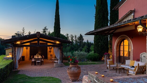 Ein Patio mit Pergola, Sitzgelegenheiten und einem großen Blumentopf.