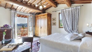 Un dormitorio con una cama grande, vigas de madera en el techo, un armario y vistas al exterior.