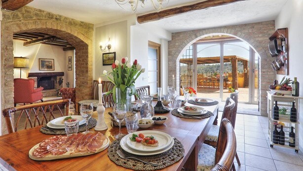 Comedor con arco de piedra, vigas de madera y vistas al exterior.